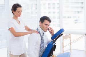 Businessman having back massage while talking on the phone in medical office